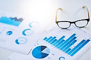 Different types of diagrams are laying on a table. The are covered by a pair of glasses.